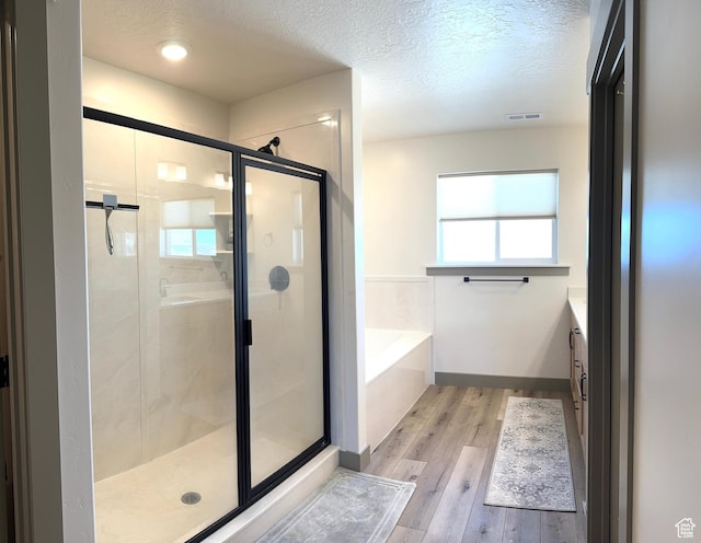 386 S Amber Field Dr Unit 508, Grantsville, UT 84029 - bathroom featuring a shower stall, wood finished floors, a textured ceiling, a bath, and visible vents