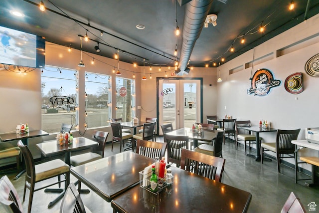 dining area featuring french doors, rail lighting, and finished concrete flooring