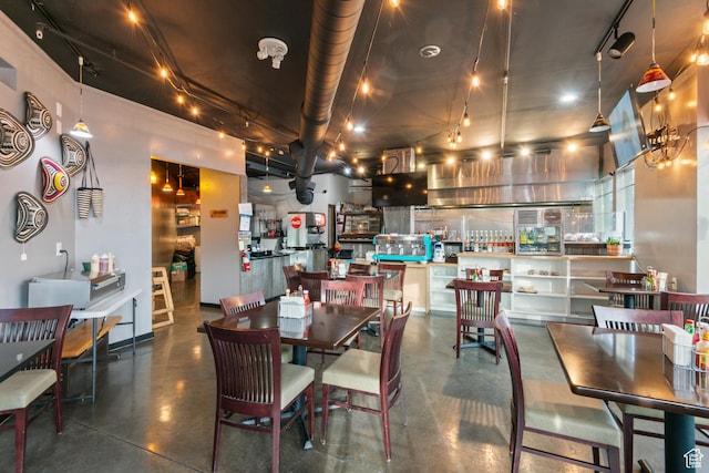 dining area with rail lighting and concrete floors