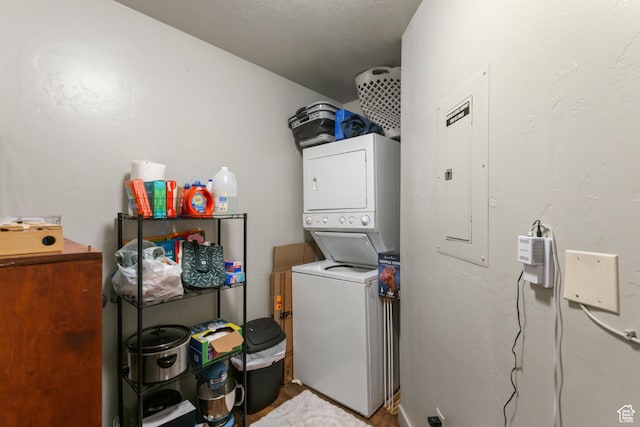 clothes washing area featuring electric panel, laundry area, and stacked washer / drying machine