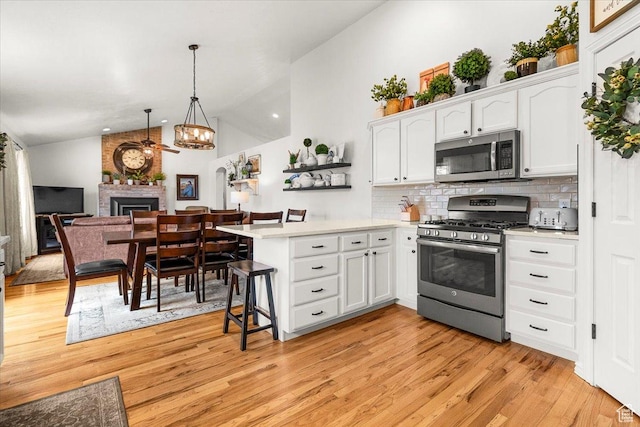 kitchen with white cabinetry, light countertops, stainless steel appliances, a ceiling fan, and a peninsula