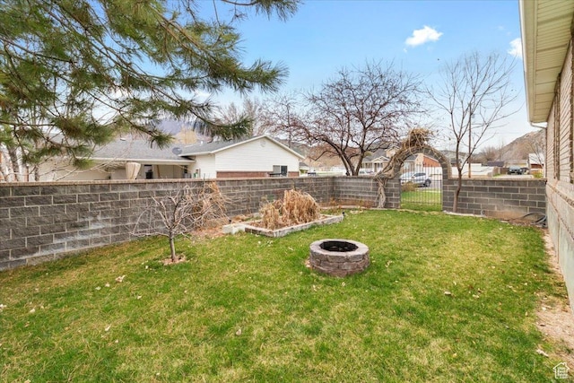 view of yard with a fenced backyard and a fire pit