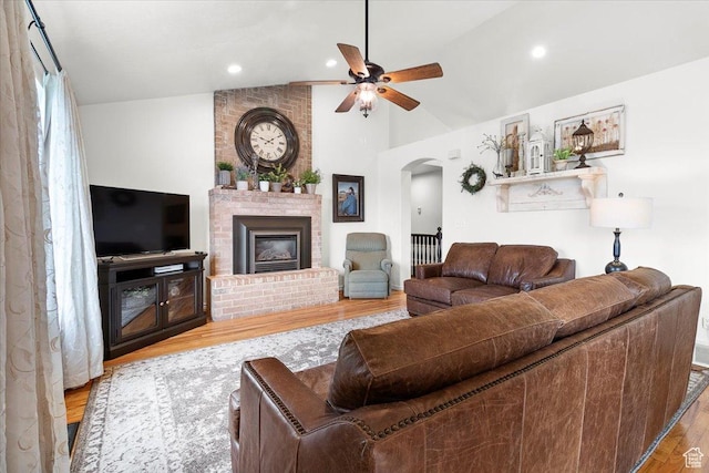 living area with a brick fireplace, recessed lighting, arched walkways, a ceiling fan, and wood finished floors