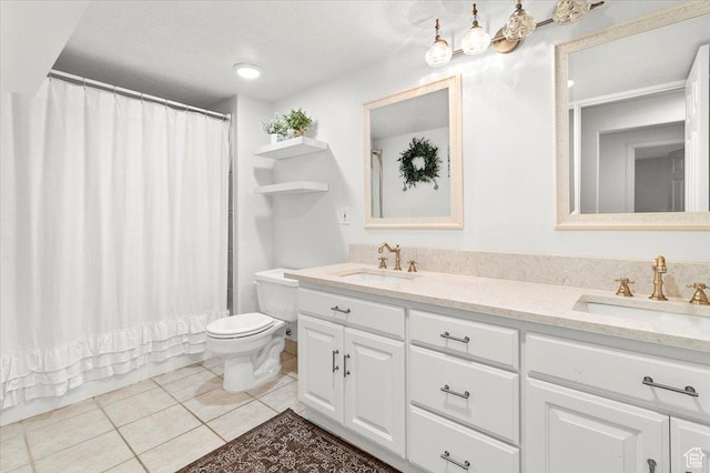 bathroom with double vanity, a sink, tile patterned floors, and toilet