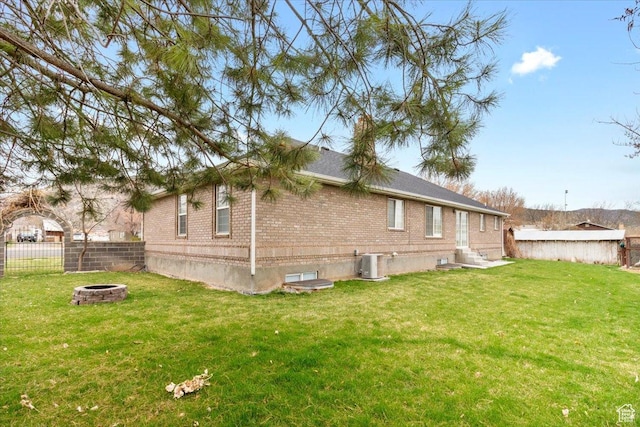 rear view of property featuring cooling unit, fence, entry steps, an outdoor fire pit, and brick siding