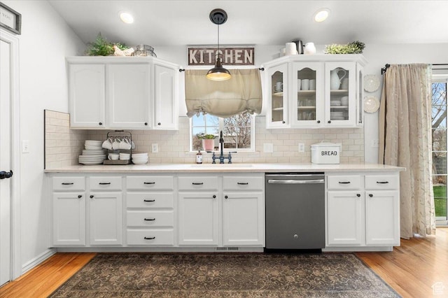 kitchen with dishwasher, wood finished floors, glass insert cabinets, white cabinetry, and a sink