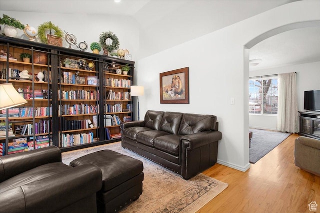 interior space featuring baseboards, wood finished floors, and arched walkways