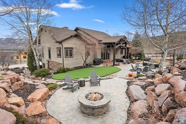 1049 S Meadow Lark Ln E, Huntsville, UT 84317 - rear view of house with a putting area, a fire pit, a patio, a chimney, and roof with shingles