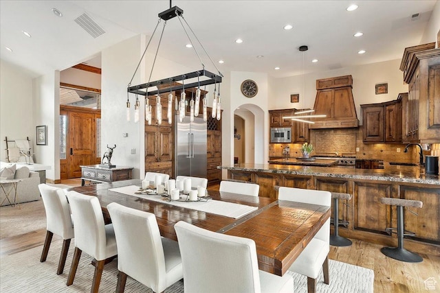 1049 S Meadow Lark Ln E, Huntsville, UT 84317 - dining area with arched walkways, light wood-style flooring, recessed lighting, and a high ceiling