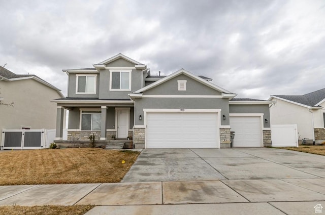 craftsman inspired home featuring stone siding, an attached garage, a gate, and stucco siding