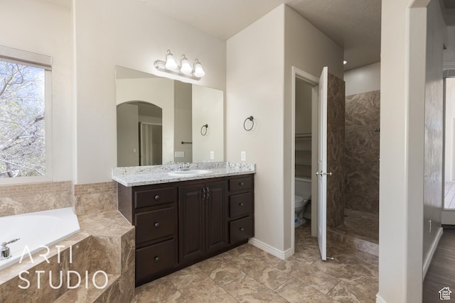 2445 E 2860 S, St George, UT 84790 - full bathroom with vanity, a tile shower, toilet, baseboards, and a garden tub