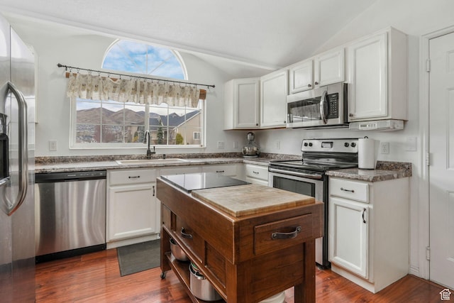 kitchen with dark wood-style flooring, white cabinets, appliances with stainless steel finishes, a sink, and vaulted ceiling