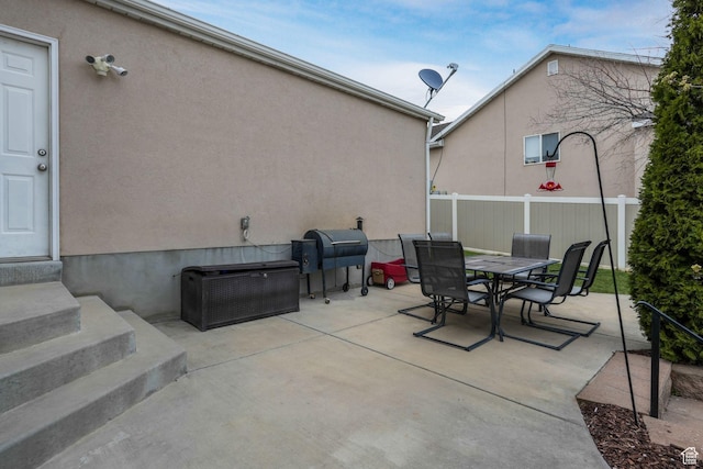 view of patio featuring a grill, outdoor dining space, entry steps, and fence