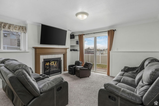 living room with baseboards, crown molding, carpet floors, and a tiled fireplace