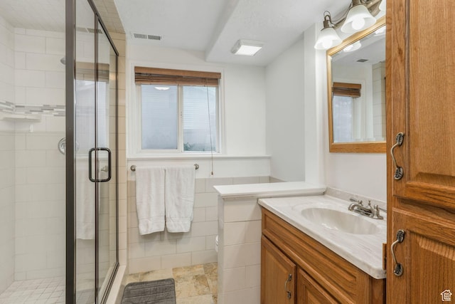 bathroom with vanity, a shower stall, tile walls, and visible vents