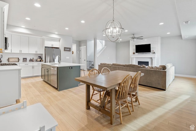 3161 N 3150 W, Plain City, UT 84404 - dining area with a fireplace, light wood-style flooring, ceiling fan with notable chandelier, visible vents, and recessed lighting