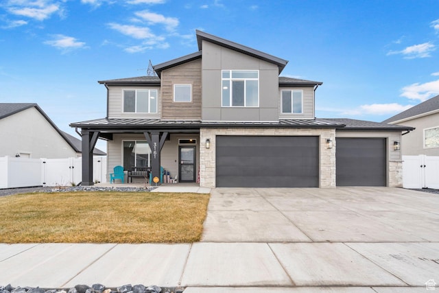 contemporary home with metal roof, fence, a garage, a standing seam roof, and a porch