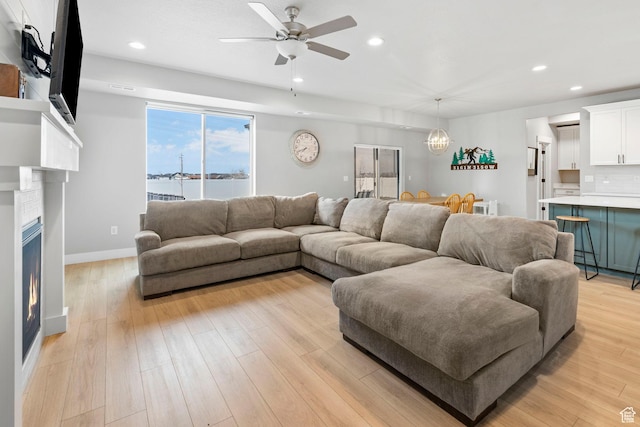 3161 N 3150 W, Plain City, UT 84404 - living area with a warm lit fireplace, light wood-style flooring, baseboards, recessed lighting, and ceiling fan with notable chandelier