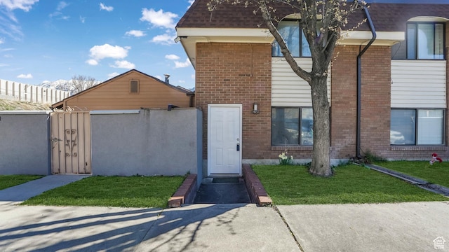 view of front facade featuring brick siding, fence, a front lawn, and a gate