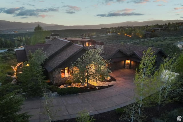 7507 Sage Meadow Rd, Park City, UT 84098 - view of front of property featuring a mountain view, a chimney, concrete driveway, stone siding, and an attached garage