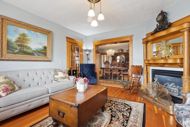 368 E 300 N, Logan, UT 84321 - living area featuring wood finished floors, a chandelier, a glass covered fireplace, and a textured ceiling