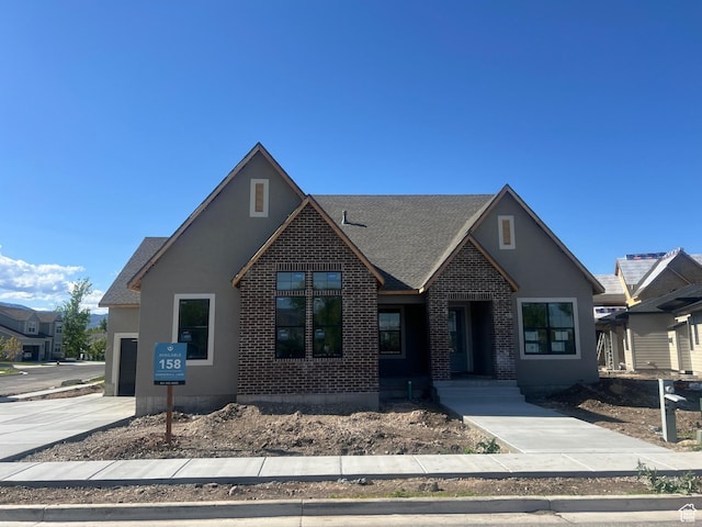 craftsman-style house with concrete driveway, brick siding, an attached garage, and a shingled roof