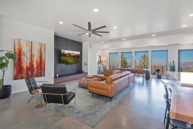 living area featuring baseboards, concrete floors, ceiling fan, and recessed lighting