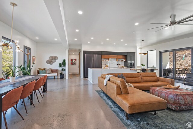 living room with a ceiling fan, recessed lighting, and concrete flooring