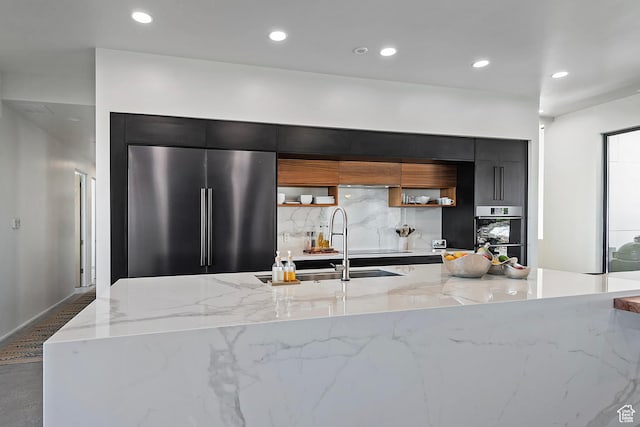 kitchen with dark cabinetry, decorative backsplash, a large island, modern cabinets, and appliances with stainless steel finishes
