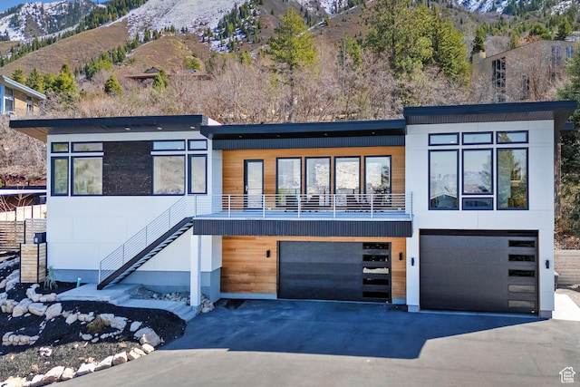 contemporary house featuring aphalt driveway, a garage, stairs, and a mountain view