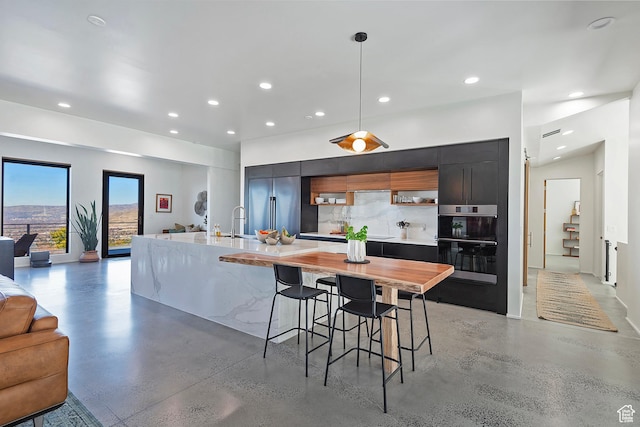 kitchen featuring stainless steel built in refrigerator, light countertops, modern cabinets, double oven, and concrete flooring