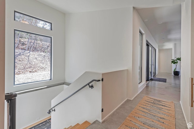 corridor featuring an upstairs landing and baseboards