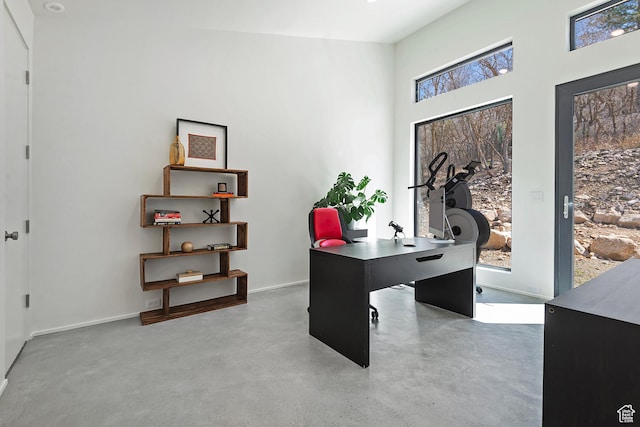 home office featuring baseboards and concrete floors