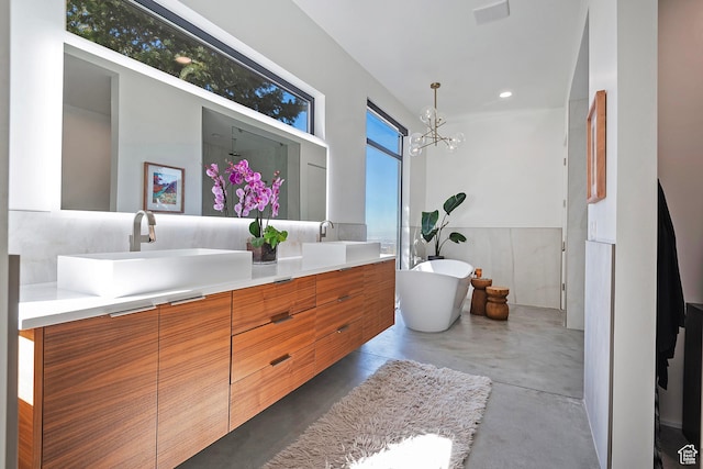 full bath featuring concrete flooring, double vanity, a sink, and a freestanding tub