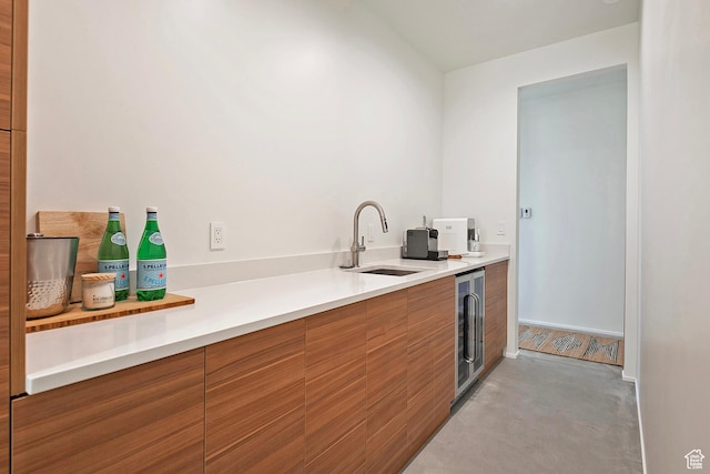 kitchen featuring light countertops, a sink, beverage cooler, modern cabinets, and brown cabinets