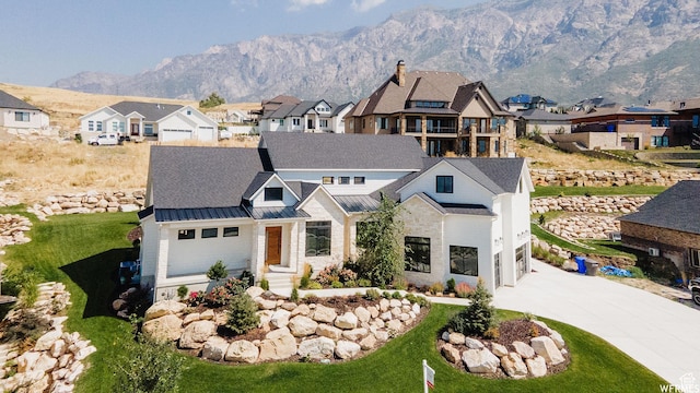 modern farmhouse style home with a standing seam roof, metal roof, a residential view, driveway, and a mountain view