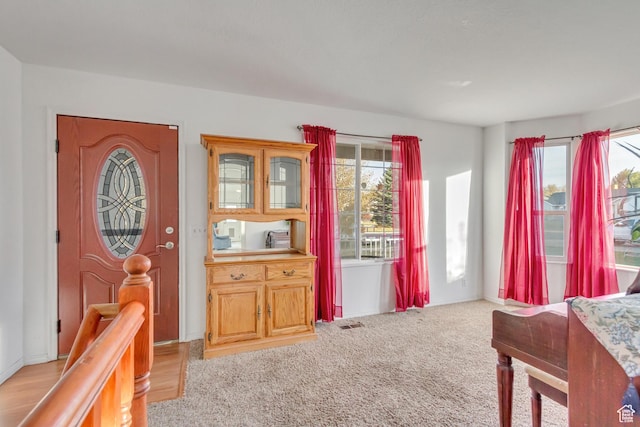 foyer entrance with light colored carpet and visible vents