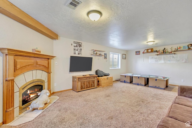 carpeted living room featuring baseboards, a textured ceiling, visible vents, and a tiled fireplace