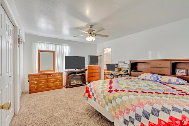 bedroom featuring a lit fireplace, ceiling fan, and carpet