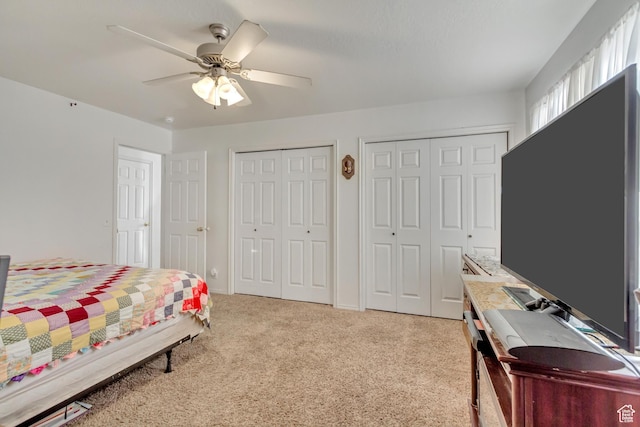bedroom featuring baseboards, multiple closets, ceiling fan, and light colored carpet