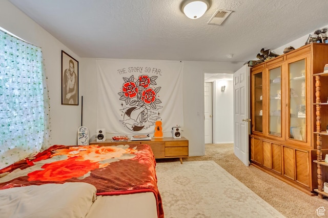 bedroom with baseboards, a textured ceiling, visible vents, and light colored carpet
