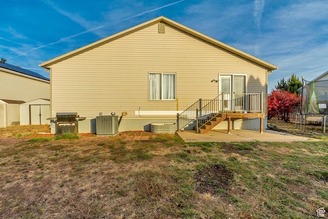 back of property with a patio area, a trampoline, a shed, cooling unit, and an outdoor structure