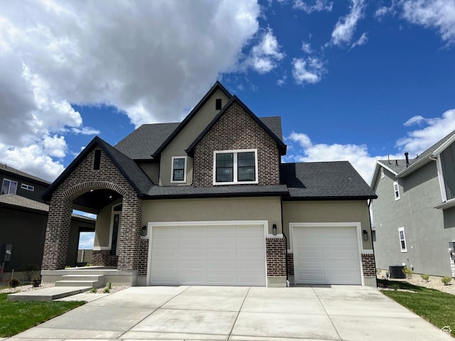 2131 N 725 W, Centerville, UT 84014 - view of front of house featuring brick siding, stucco siding, driveway, central air condition unit, and roof with shingles