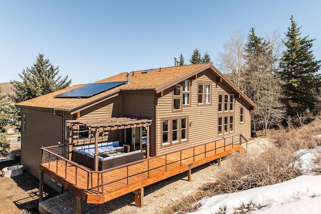 rear view of property with roof mounted solar panels, a pergola, an outdoor living space, and roof with shingles