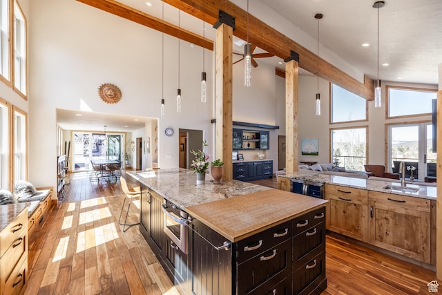 kitchen with a sink, a high ceiling, hardwood / wood-style floors, and open floor plan