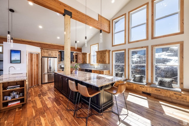 kitchen with freestanding refrigerator, high vaulted ceiling, a spacious island, and light stone counters