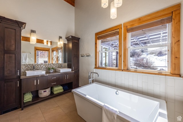 full bath featuring a sink, tile patterned floors, tasteful backsplash, and a freestanding bath