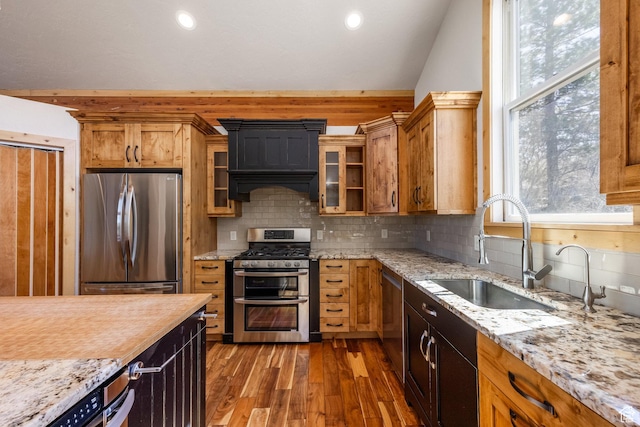 kitchen featuring appliances with stainless steel finishes, decorative backsplash, a sink, and dark wood-type flooring