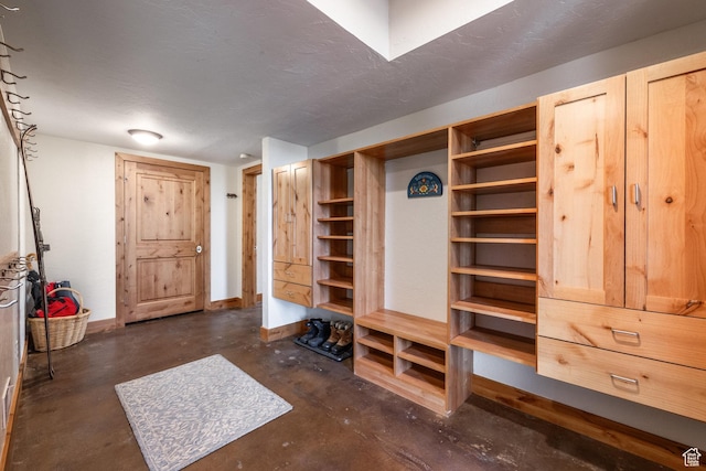 mudroom with baseboards and concrete flooring