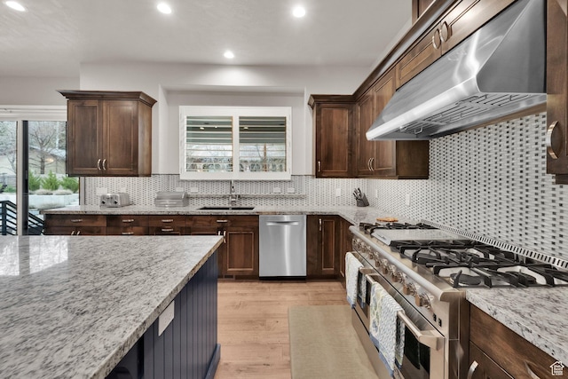 8165 S Willow Creek Cv E, Cottonwood Heights, UT 84093 - kitchen with light wood finished floors, light stone countertops, under cabinet range hood, a sink, and stainless steel range